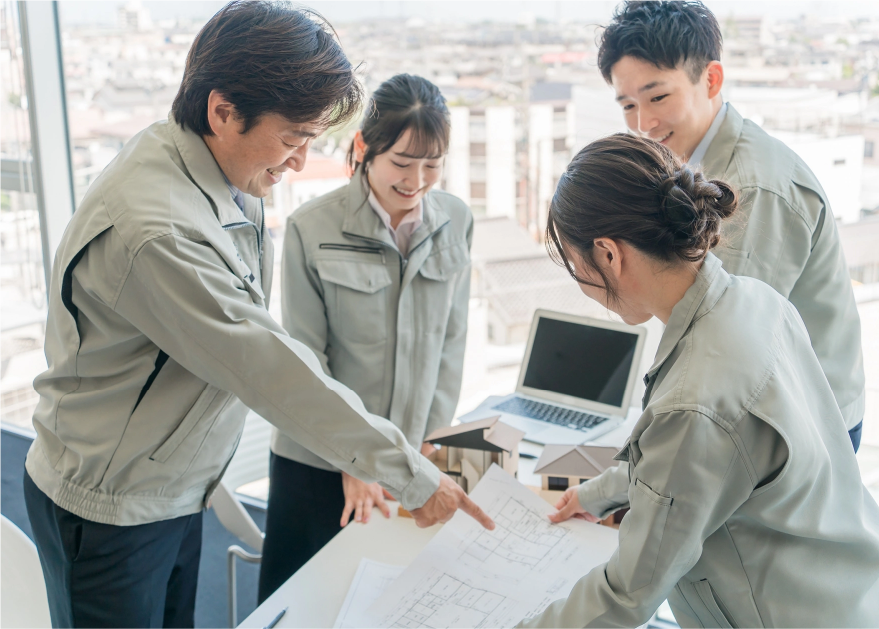 図面を見ながら話す4人の作業着の男女の写真